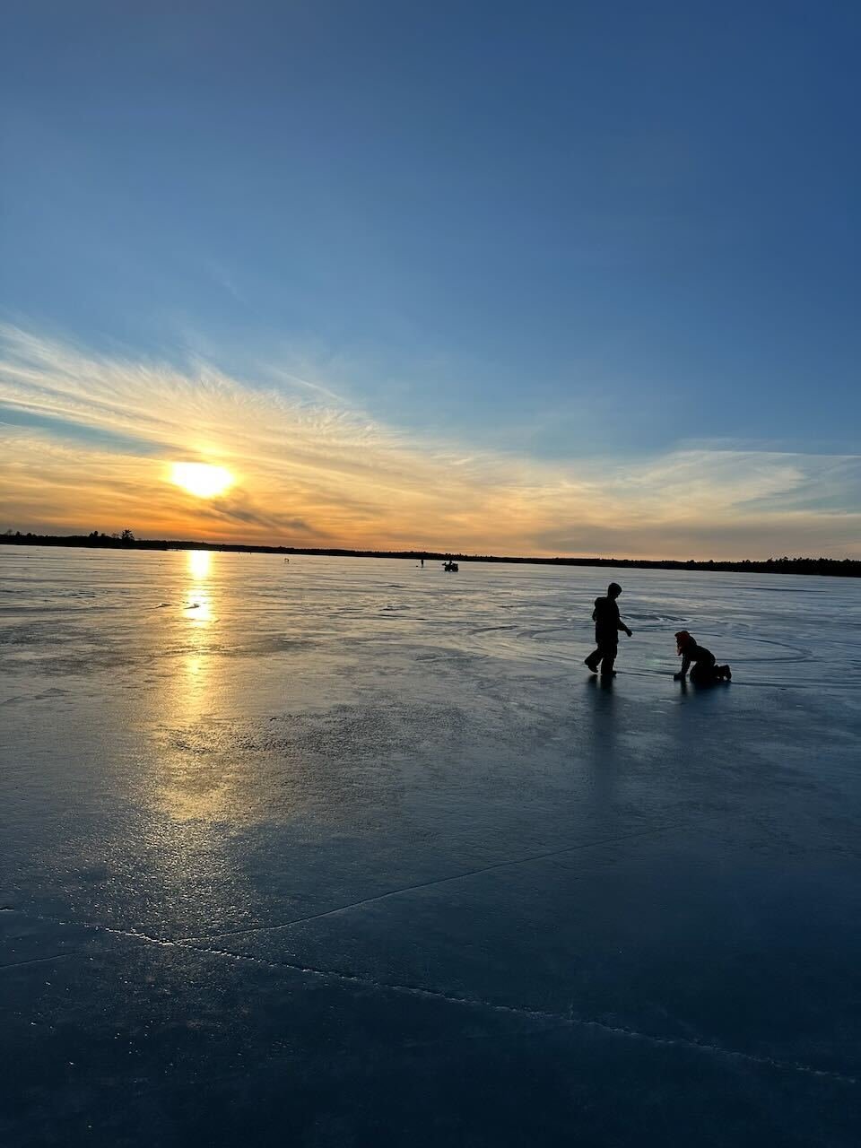 A frozen lake that looks like moon with the silhouette of two boys playing